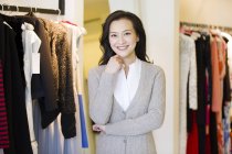 Китайська жінка, стоячи в магазин одягу і дивлячись в камери — стокове фото