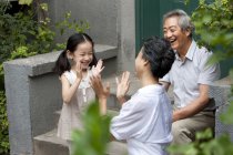 Chinese elementary age girl playing with grandparents on street — Stock Photo