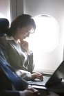 Chinesische Geschäftsfrau benutzt Laptop im Flugzeug — Stockfoto