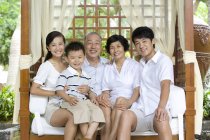 Portrait of Chinese family with boy sitting on bench on vacation — Stock Photo