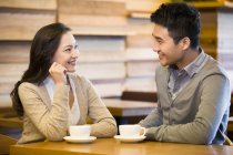 Chinese couple chatting in cafe with cups of coffee — Stock Photo