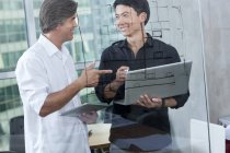 Male designers with laptop and digital tablet in board room — Stock Photo