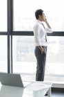 Chinese businessman talking on phone in office — Stock Photo