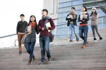 Chinesische Studenten gehen die Stufen des Universitätsgebäudes hinunter — Stockfoto
