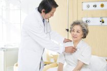 Médecin chinois utilisant le stéthoscope sur le patient à l'hôpital — Photo de stock