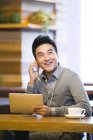 Homem chinês ouvindo música com tablet digital no café — Fotografia de Stock