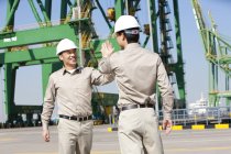 Male Chinese shipping industry workers high-fiving — Stock Photo