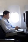 Hombre de negocios chino usando smartphone en avión - foto de stock