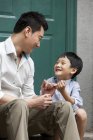 Chinese father and son holding little fingers on porch — Stock Photo
