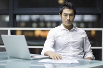 Китайський бізнесмен, сидячи на столі в офісі — стокове фото