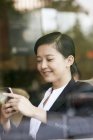 Китайская предпринимательница использует смартфон в кафе — стоковое фото