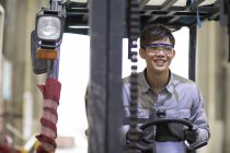 Chinese worker driving forklift at industrial factory — Stock Photo