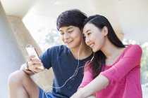 Pareja china escuchando música en un smartphone juntos - foto de stock