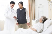Китайська, робоче місце лікаря стоячи зі старшим пара в лікарні — стокове фото