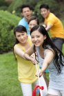 Chinese young adult friends pulling rope in park — Stock Photo
