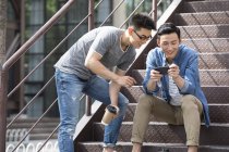 Chinese friends using smartphone at street — Stock Photo