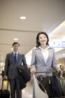 Chinese business people pulling luggage in airport — Stock Photo