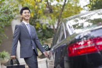 Jovem empresário chinês abrir porta do carro — Fotografia de Stock