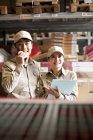 Male and female Chinese warehouse workers looking at boxes and using walkie-talkie — Stock Photo