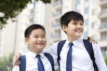 Compagni di classe allegri in uniforme scolastica guardando la vista — Foto stock