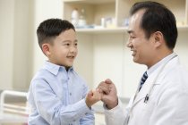 Китайського хлопчика і лікар, роблячи мізинець обіцянку — стокове фото