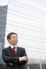 Retrato de empresário chinês maduro na frente da construção de negócios — Fotografia de Stock