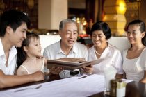 Chinesische Mehrgenerationenfamilie schaut sich Speisekarte im Restaurant an — Stockfoto