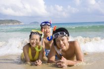 Jeune famille avec des masques de plongée allongés sur la plage — Photo de stock
