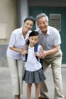 Chinese schoolgirl with grandparents posing on street — Stock Photo