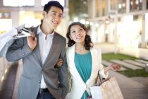 Young Chinese couple shopping in evening city — Stock Photo