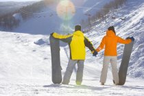 Rear view of young couple with snowboards — Stock Photo