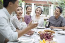 Familia china hablando en la mesa de comedor en el patio - foto de stock