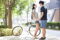 Chinesisches Paar hält mit Fahrrad Händchen auf dem Campus — Stockfoto