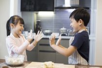Irmãos chineses brincando com farinha na cozinha — Fotografia de Stock