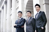 Équipe d'affaires chinoise debout devant le bâtiment — Photo de stock