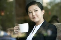 Chinese businesswoman drinking coffee in cafe — Stock Photo