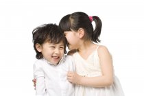 Asian siblings whispering and smiling on white background — Stock Photo
