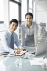 Китайський бізнес-леді і бізнесмен, стоячи в офісі — стокове фото
