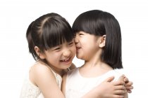 Crianças chinesas sussurrando e sorrindo em fundo branco — Fotografia de Stock