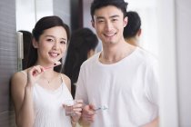Couple chinois brossant les dents dans la salle de bain — Photo de stock