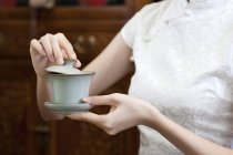 Жінка в традиційному чонгсам тримає чашку чаю — стокове фото