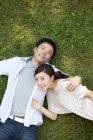 Вид зверху молода Китайська пара лежить на траві — стокове фото