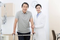 Médecin chinois aidant le patient avec walker — Photo de stock