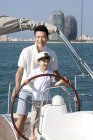 Chinese father and son sailing on yacht in bay — Stock Photo