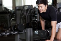 Chinese man lifting dumbbell in gym — Stock Photo