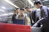 Uomini d'affari e ingegneri che utilizzano laptop in fabbrica industriale — Foto stock