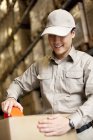 Male Chinese warehouse worker packing box — Stock Photo