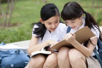 Écolières assis sur les marches et la lecture de livres — Photo de stock