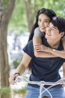 Chinese couple riding bicycle and embracing on street — Stock Photo