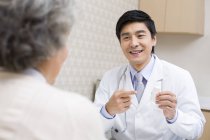 Médico chino explicando la dosis de medicamento al paciente — Stock Photo